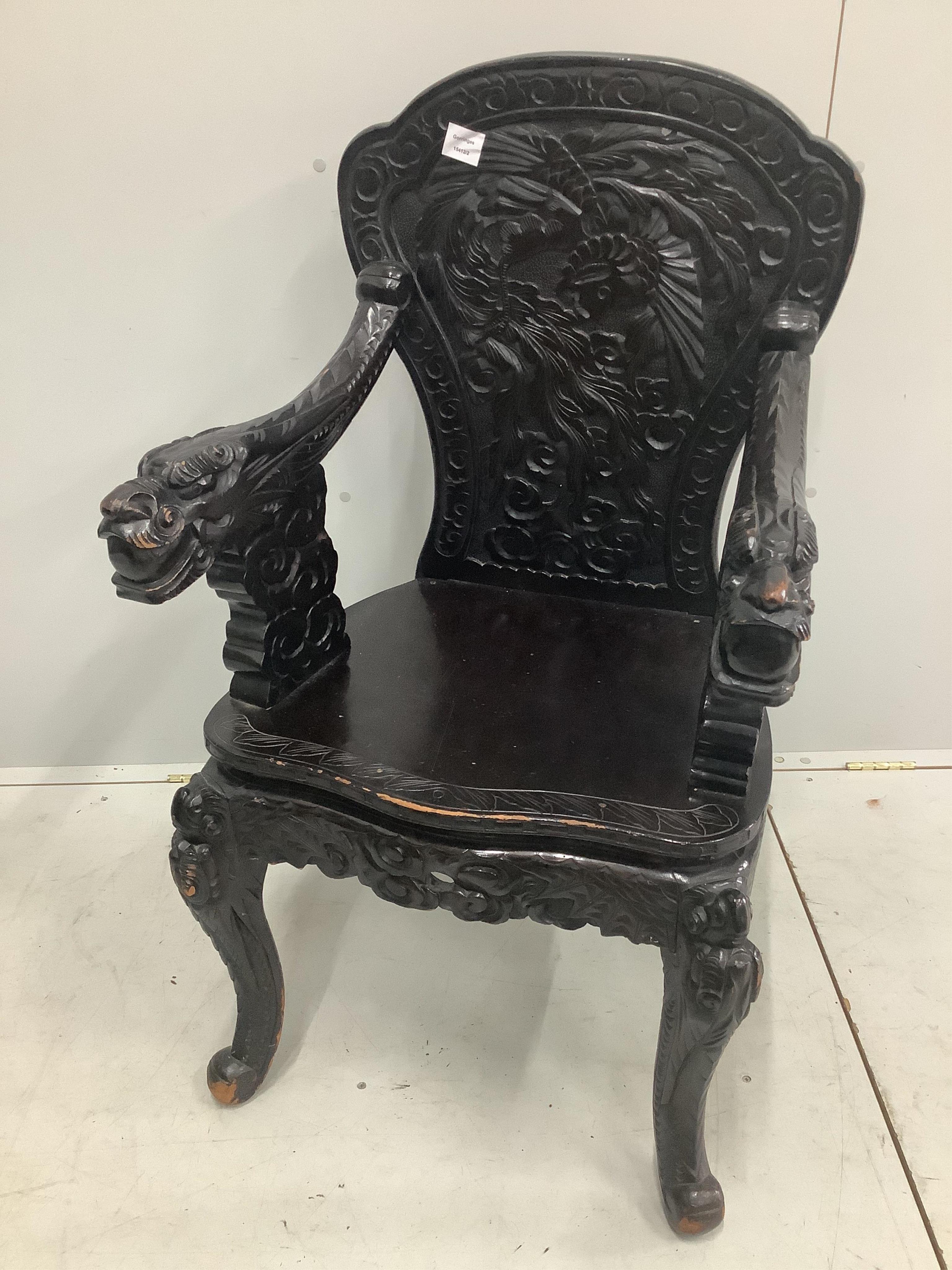 An early 20th century Chinese ebonised and carved hardwood elbow chair with dragon arms, width 60cm. Condition - poor